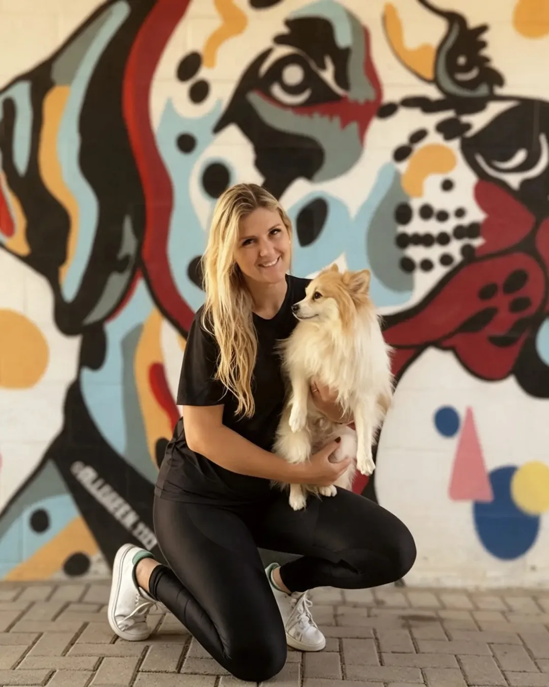 Vanessa, sócia da Pet K-9, com um cão no mural colorido