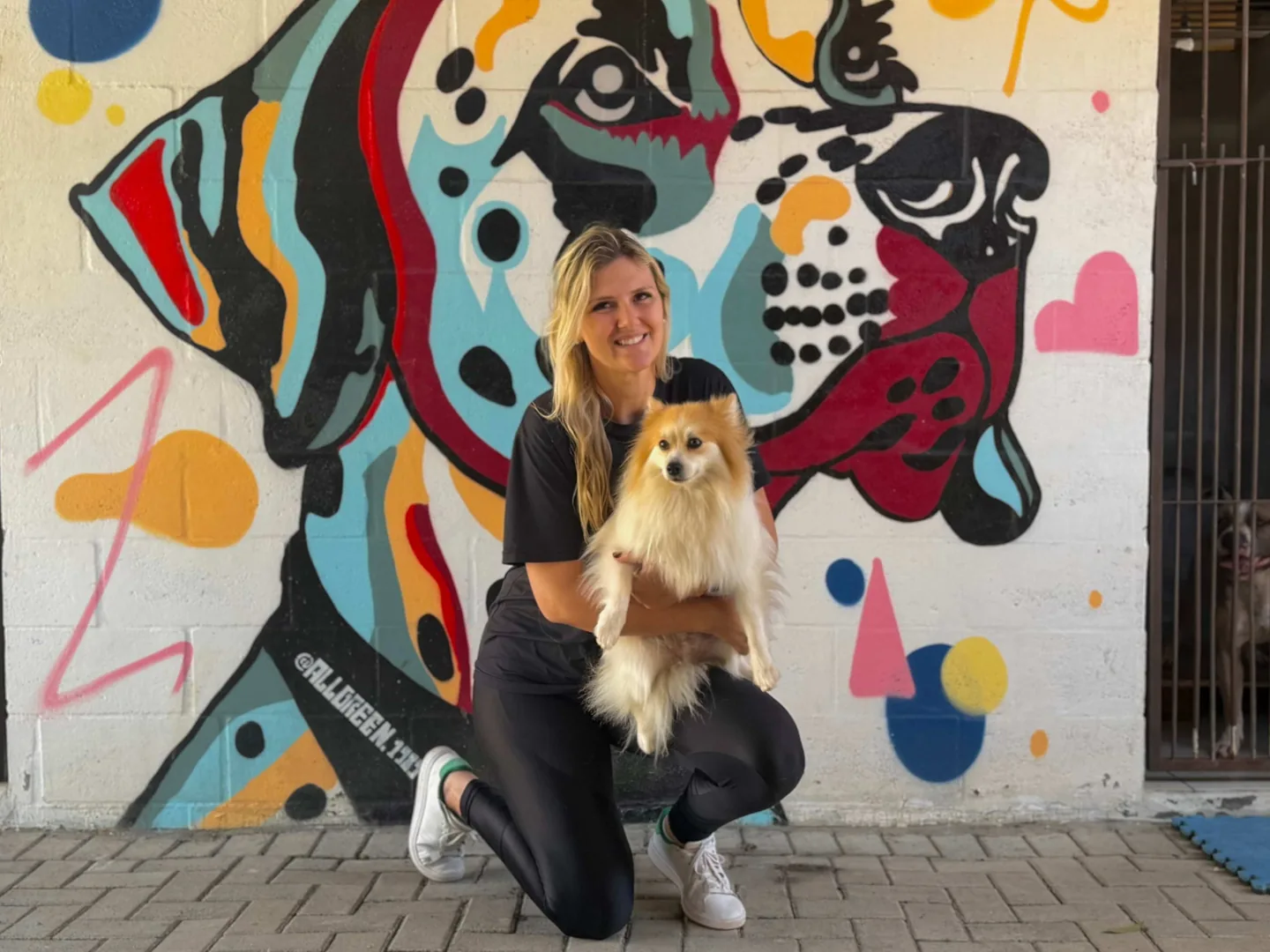 Vanessa, da Pet K-9, com um cão hospedado diante do mural do canil